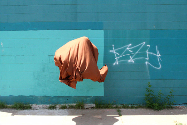 A floating rust-colored sheet of fabric seems to float, unaided, about 4 feet off the ground. The fabric is billowed and folded as though occupied inside, yet there's no evidence of a mass or volume that would occupy it.