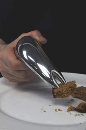 a close up of a hand using a proto-fork—a wider base for grasping, and two prongs at the end for spearing food.