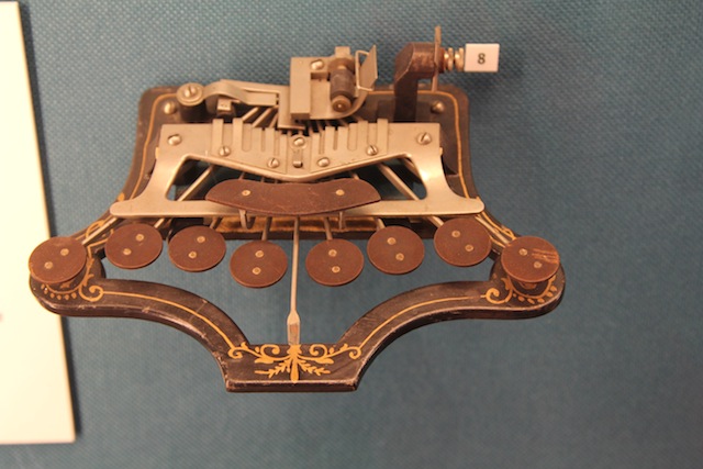 A simple metal Brailler from the nineteenth century, with 8 keys for typing and the look of a musical instrument