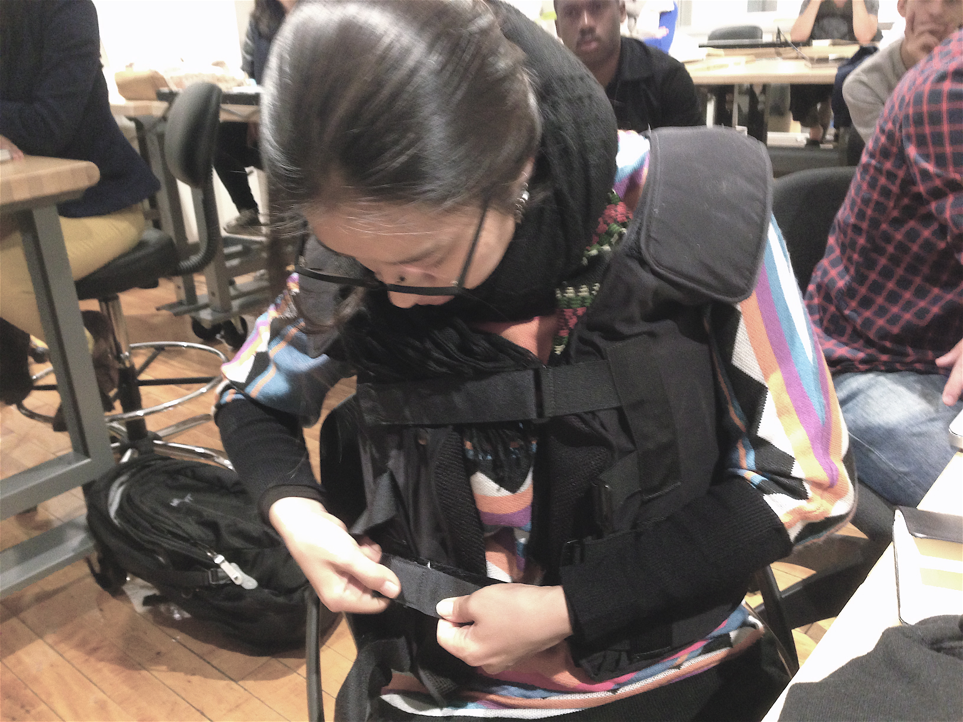 A female student tries on the vest, finding the hook attachments to secure together across her chest.