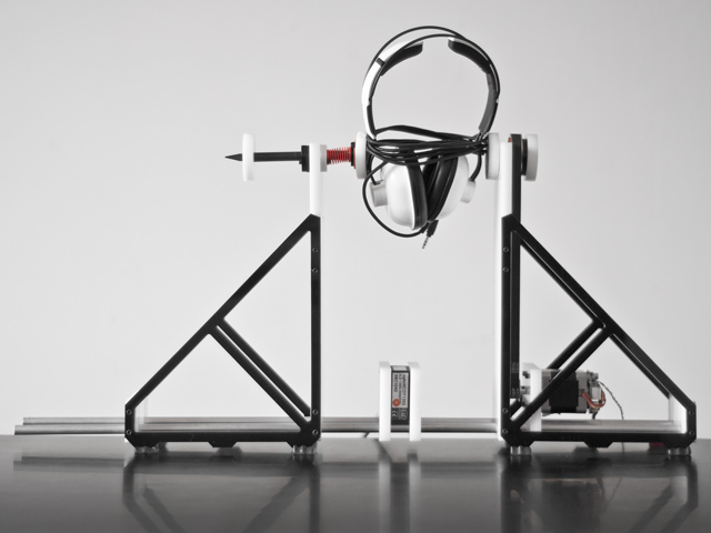 the same instrument, holding a large pair of headphones.