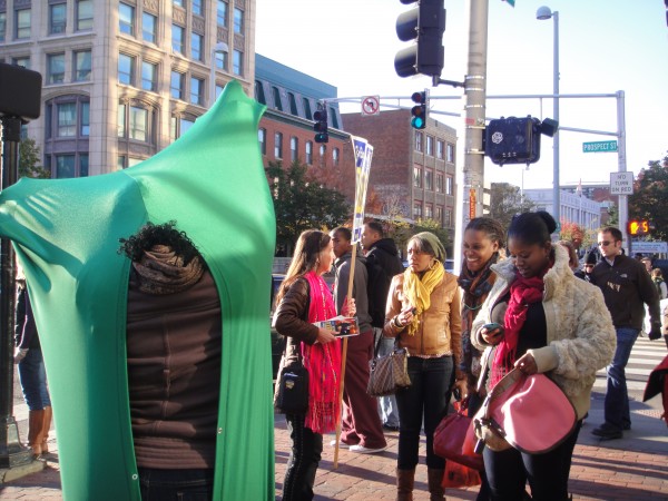 A woman in Central Square dons the green fabric envelope, while her friends look on.