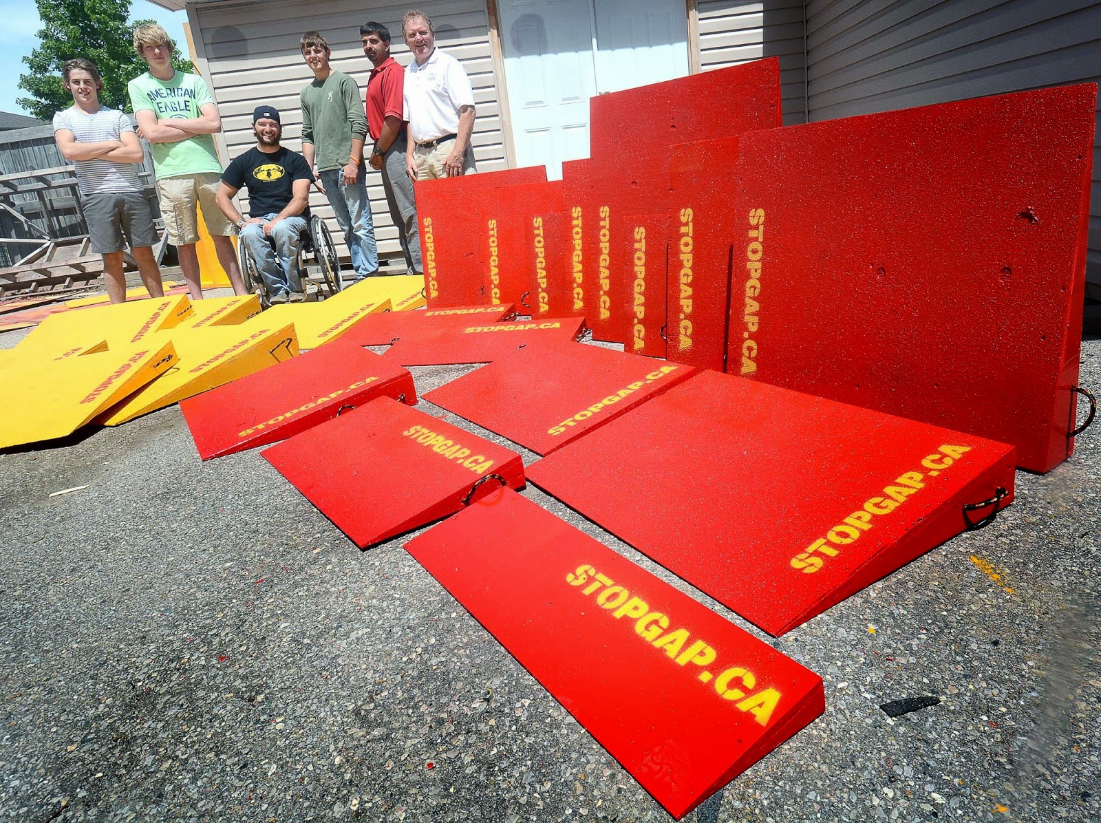 A shot of members of the Stop Gap project, with a dozen bright red or yellow temporary ramps, all reading stopgap.ca.