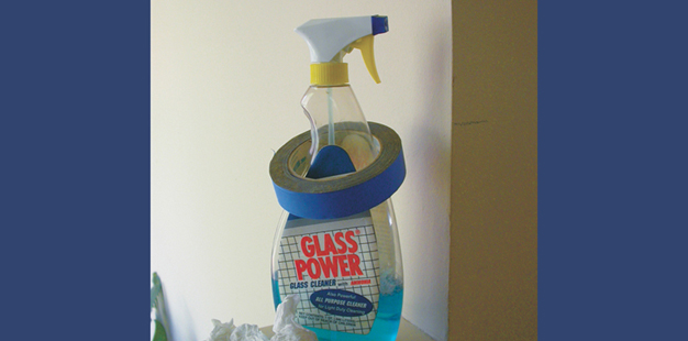 A roll of painter's tape fits perfectly around the neck of a spray bottle of household cleaner.