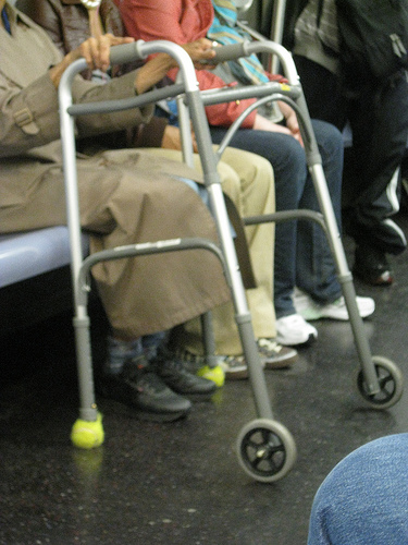 a commonly used walker mobility aid, with wheels on front and tennis balls on the back two feet